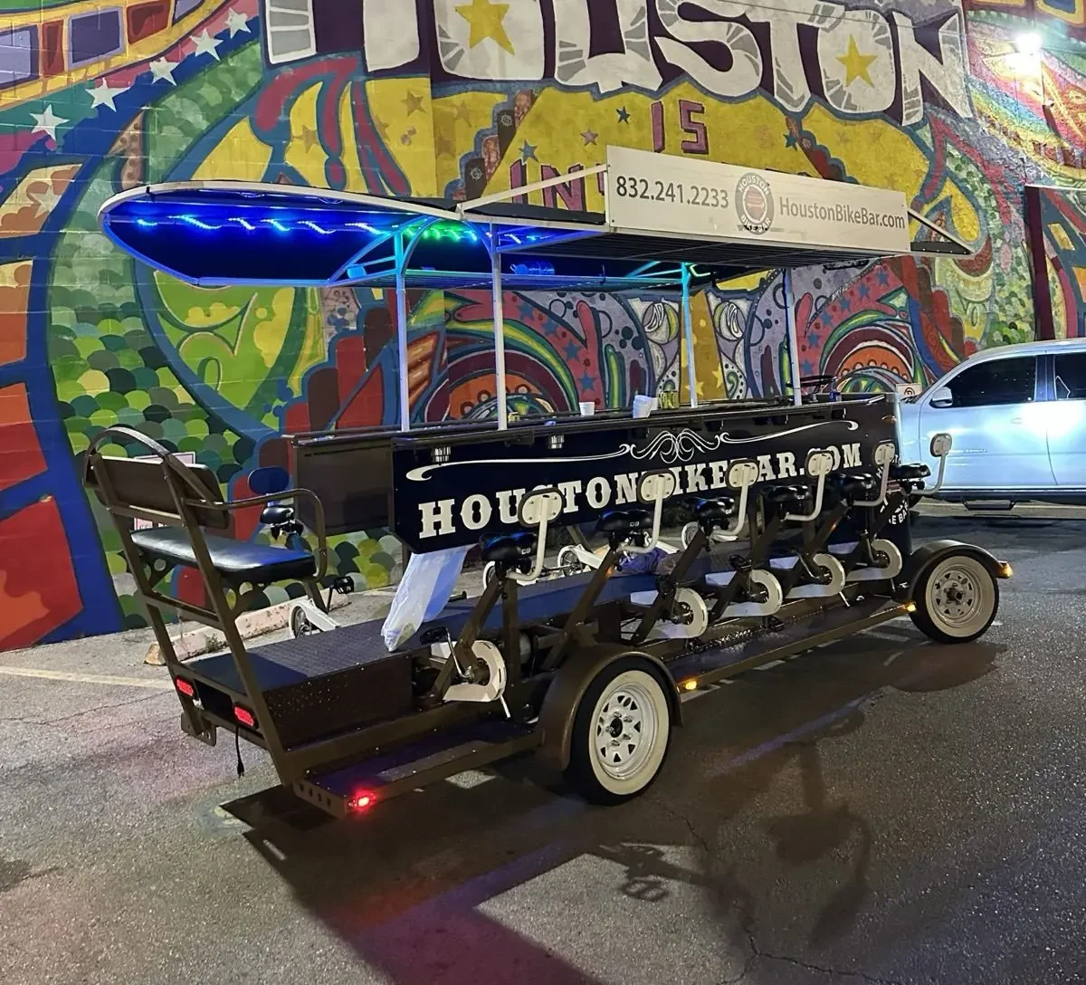 The Houston Bike Bar lit up at night in front of a Houston mural